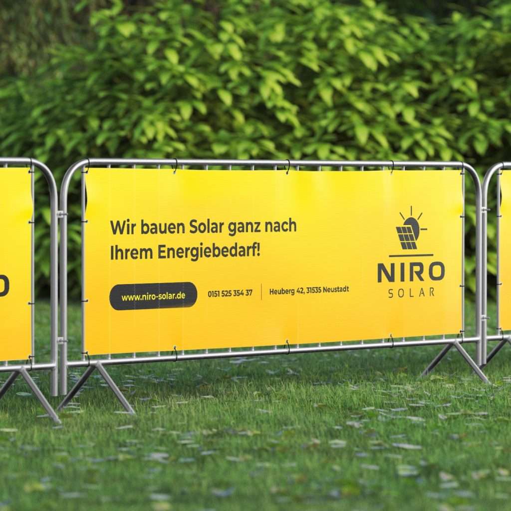 Zaun steht auf einer Wiese und zeigt ein Bannerdesign von Niro Solar GmbH