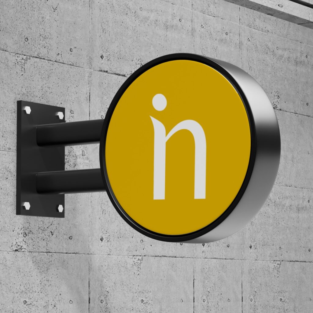 Rundes schwarzes Schild aus einer Betonwand raushängend. In dem runden Schild sieht man das Logo der Marke nido concept.